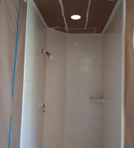 Shower stall with white tile walls and a built-in soap dish.