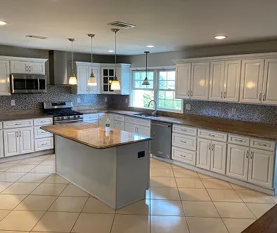Spacious kitchen with white cabinets, granite countertops, and a central island.