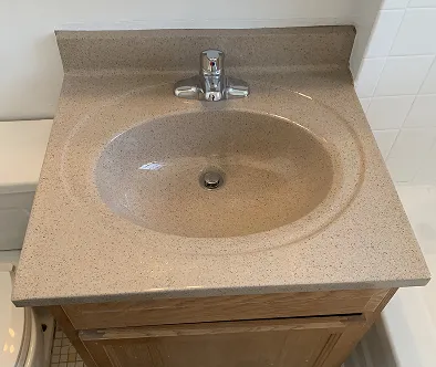 Bathroom vanity with speckled countertop and chrome faucet
