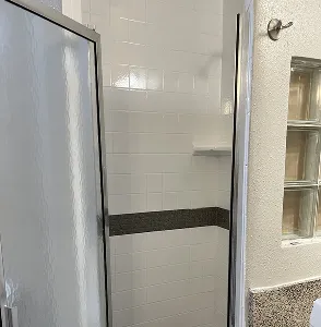 Modern bathroom with white tiled shower stall and glass door