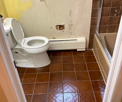 Bathroom with toilet, bathtub, and radiator.