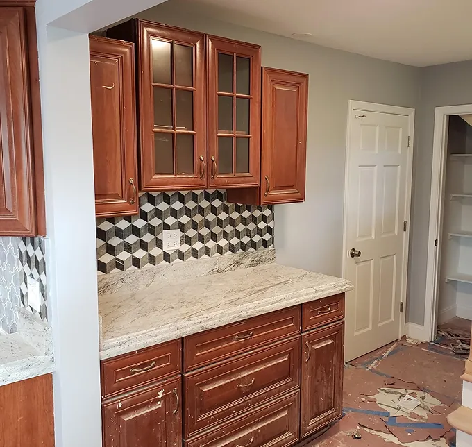 Kitchen with cherry cabinets, granite countertops, and geometric tile backsplash.