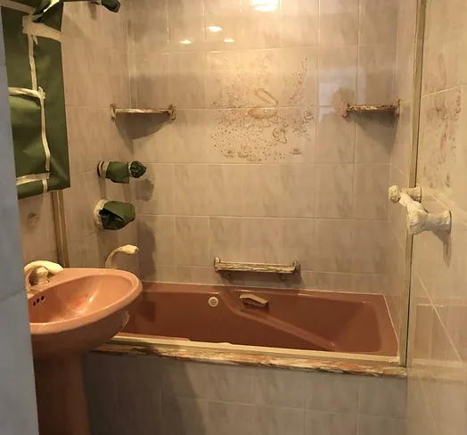Bathroom with pink sink and brown bathtub, tiled walls with floral design.