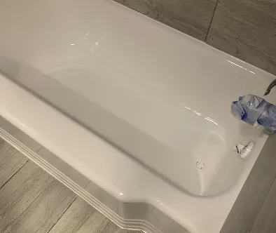 White bathtub with a blue plastic bag on the faucet.