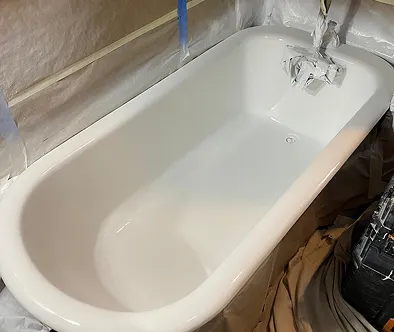 White bathtub being refinished with protective coverings and tape.