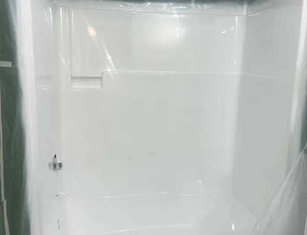 White bathtub with shower controls and plastic sheeting.