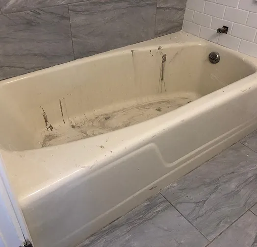 Dirty bathtub with stained interior and tiled walls
