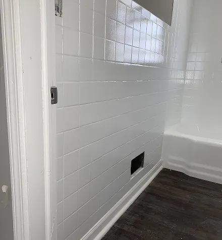 White tiled bathroom with dark wood floor and vent