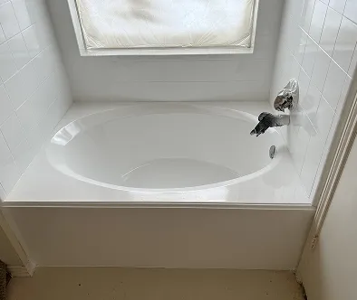 White oval bathtub with chrome faucet and tiled walls.
