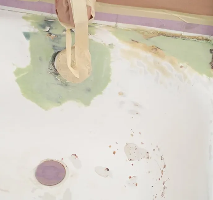 Person applying putty to a damaged bathtub with tape.