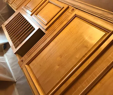 Close-up of wooden cabinet doors with decorative trim and a vent.