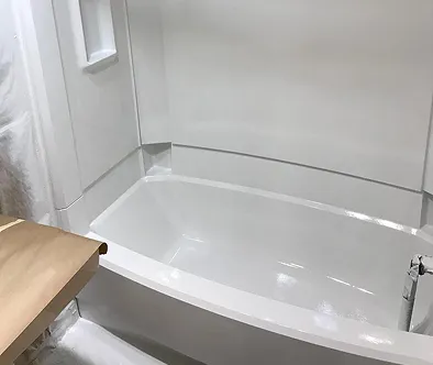 White bathtub with shower surround, partially covered with protective paper.